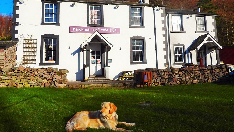 A dog relaxing on the grass in front of the Woolpack Inn in Boot, a dog-friendly pub in the Eskdale Valley in the Lake District